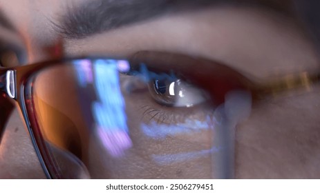 Close-up of a developer wearing glasses, coding on a computer. Code and analytics reflections in the glasses emphasize focus on cybersecurity and software development. - Powered by Shutterstock