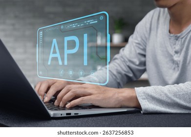 A close-up of a developer's hands typing on a laptop with a digital API interface projected above, highlighting modern programming and technology concepts in a workspace.