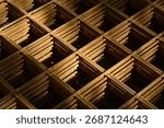  A close-up, diagonal view highlights the rusty, stacked layers of welded wire mesh (rebar grid) used for concrete reinforcement, creating a repeating geometric pattern with deep shadows