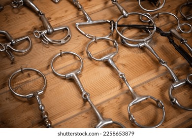 Closeup of Different Types of Metal Horse Bits Hanging on the Wall in Professional Sport Stable Tack Room. Equestrian Equipment Theme.