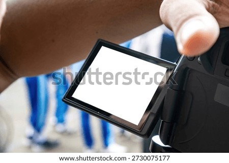 Close-up of a digital camera LCD screen with a white blank space for mockup, held by a photographer