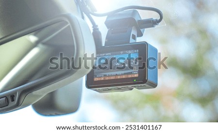 Close-Up Of Digital Camera On Windshield In Car. Dashcam mounted in the windshield with lens flare.