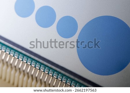 Close-up of a digital display featuring a sequence of blue circles in increasing size, connected to a circuit with visible pins.