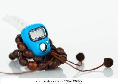 Close-up of digital prayer beads hand tally counter isolated over white. Used by muslims in worship especially in holy Ramadhan. Traditional beads in visibility.  Focus on blue digital counter.