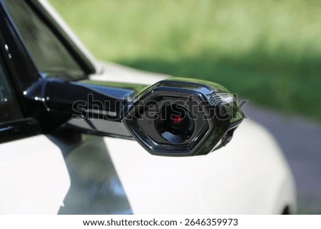 Close-up of a digital side mirror camera on a modern car, showcasing advanced automotive design and futuristic technology.

