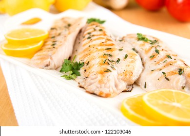 Closeup Of Dinner Plate With Grilled White Fish And Lemons