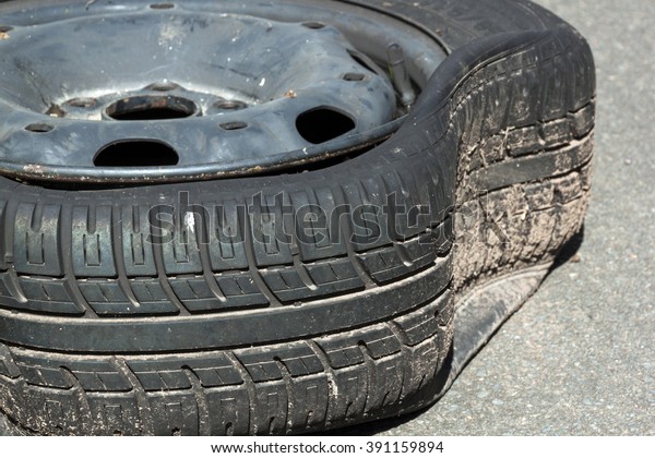 closeup of dirty damaged deflated tire after blowout\
caused by pot hole in\
road