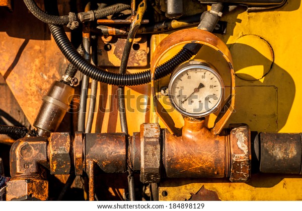 Close-up of dirty hydraulic machine with pressure\
clock. Horizontal\
image.