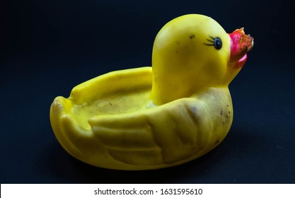 Closeup Of Dirty Yellow Rubber Duck With Damaged Beak Isolated On Dark Blue Background, Space For Text.