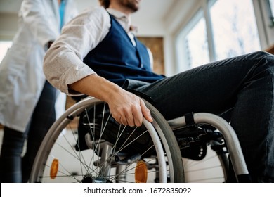Close-up of disabled man in wheelchair and a nurse at home. 