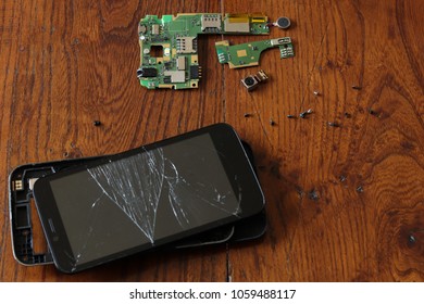 Closeup To A Dismantled Smartphone On A Wood Table.