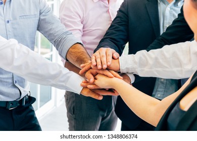 Close-up of diverse business people of men and woman putting hands together - collaboration and togetherness in work office concept
