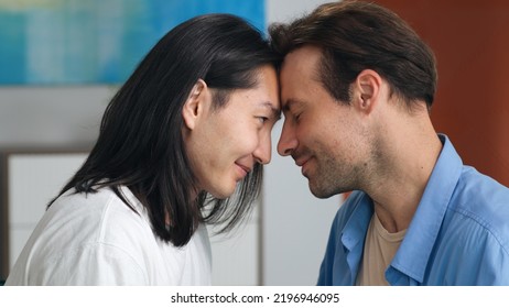 Closeup of diverse gay couple touching foreheads and look into each other eyes. Close up of multiethnic homosexual partners embrace and smile - Powered by Shutterstock