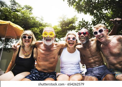 Closeup of diverse senior adults sitting by the pool enjoying summer together - Powered by Shutterstock