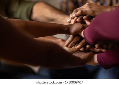 Closeup of a diverse team of businesspeople sitting in a huddle with their hands together in an office - Shutterstock ID 1730009407