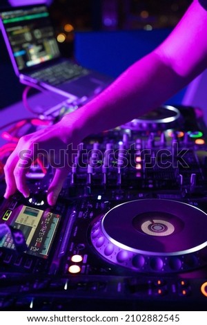Close-Up of Dj Mixer Controller Desk in Night Club Disco Party. DJ Hands touching Buttons and Sliders Playing Electronic Music . High quality photography.