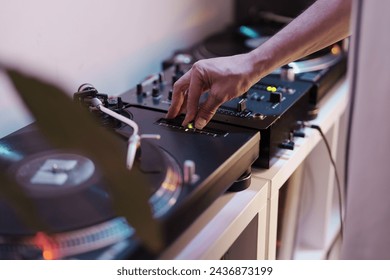 Close-up of a DJ's hand adjusting settings on a turntable during a live music set.