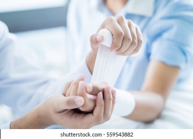 Close-up doctor is bandaging upper limb of patient. - Powered by Shutterstock