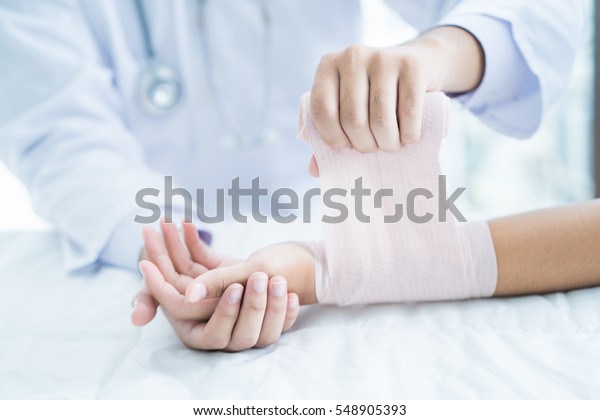 Close-up\
doctor is bandaging upper limb of\
patient.
