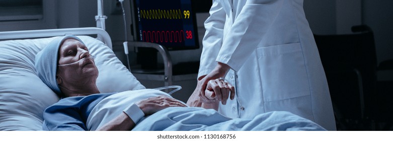 Close-up Of A Doctor Checking Pulse Of His Dying Of Cancer Patient In The Hospital