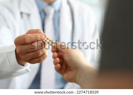 Closeup of doctor hand giving medical pills to patient