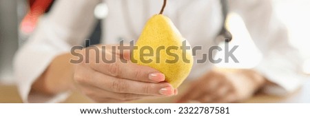 Close-up of doctor holding ripe yellow pear in hand. Healthy food, diet, vitamins and balanced nutrition concept