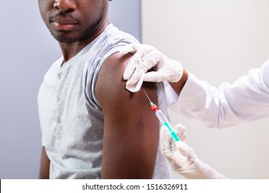 Close-up Of Doctor Injecting Vaccine Into Patients Arm With Syringe