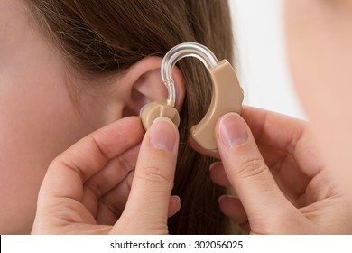 Close-up Of Doctor Inserting Hearing Aid In The Ear Of A Girl