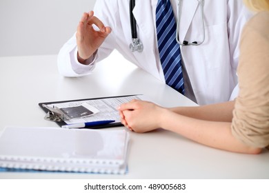 Close-up of a doctor man hands showing ok sign while consulting patient