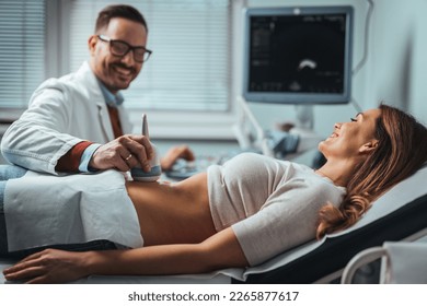 Close-up Of Doctor Moving Ultrasound Probe On Pregnant Woman's Stomach In Hospital. Woman undergoing ultrasound scan in clinic. Professional doctor screening of pregnant woman by ultrasound.