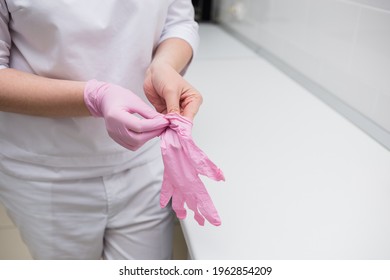 Close-up Of A Doctor Putting Disposable Pink Gloves On His Hands