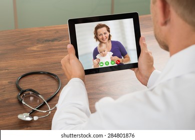 Close-up Of Doctor Talking To Patient Over Laptop Video Chat At Desk