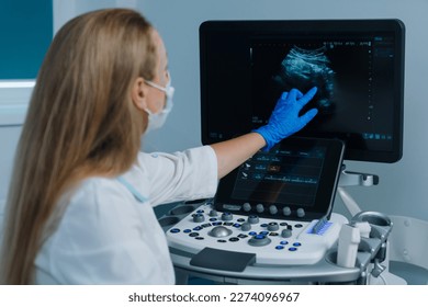 A close-up of a doctor who points with his hand at the screen of a modern ultrasound machine in a hospital. Doctor's appointment at the clinic. - Powered by Shutterstock