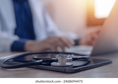 Close-up of doctor working on laptop computer with digital tablet on table in doctor's office medical and health care concept