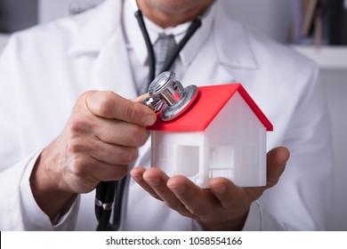 Close-up Of A Doctor's Hand Holding Stethoscope On House Model - Powered by Shutterstock