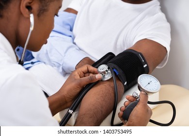 Close-up Of Doctor's Hand Measuring Blood Pressure Of Male Patient