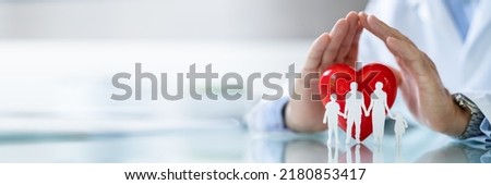 Close-up Of A Doctor's Hand Protecting Family Cut Out With Red Heart Shape