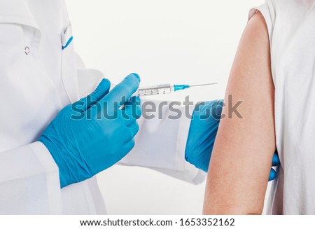 Close-up of doctor's hands in blue rubber gloves giving shot to patient, isolated white backgroud