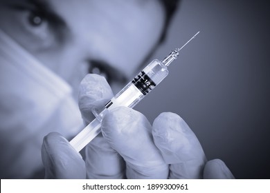 Close-up doctor's hands with gloves holding syringe and vaccine for prevention and treatment of covid-19 virus or seasonal flu