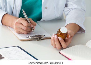 Close-up Of Doctor's Hands Writing Prescription And Holding Bottle With Pills. Healthcare, Medical And Pharmacy Concept.