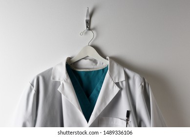 Closeup of a Doctors White Lab Coat and scrubs on a hanger .
