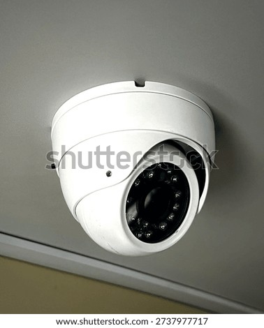 Close-up of dome CCTV security camera installed on interior ceiling for surveillance and safety monitoring.