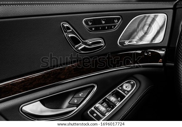 Closeup of a door control panel in a new car. Arm\
rest with window control panel, door lock, seat adjustment  \
buttons, and mirror\
control