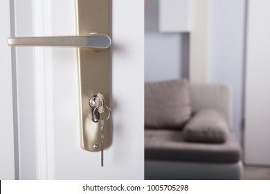 Close-up Of Door Handle With Inserted Key In The Keyhole And House