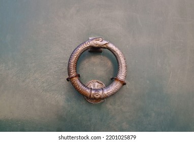 Close-up of a door knocker in the shape of an uroboros, an ancient symbol depicting a serpent (or dragon) eating its own tail, often interpreted as a symbol for eternal cyclic renewal, Italy - Shutterstock ID 2201025879