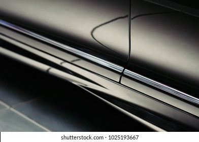 Closeup Door Of A Modern Luxury Black Car With Beautiful Reflections. Exterior Details. Abstract Shiny Dark Chrome Surface With Cute Reflections