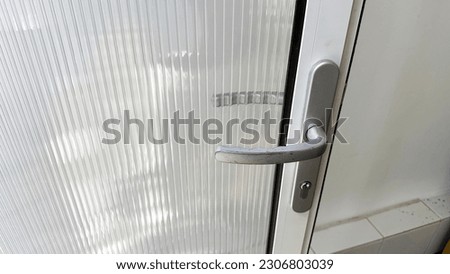 Close-up of doors and vintage silver handles of white door frames and translucent windows