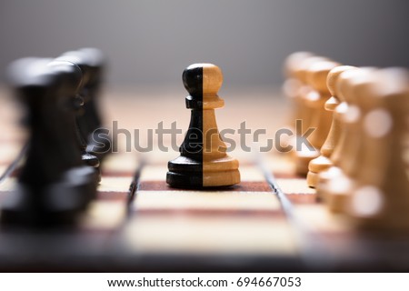 Closeup of double color pawn amidst other chess pieces on board game