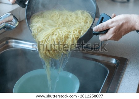 Close-up of draining freshly cooked spaghetti into a colander with steaming pasta and hot water