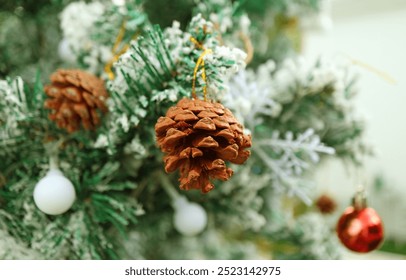 Closeup of a Dried Pine Cone Ornament Hanging on a Snow Covering Christmas Tree - Powered by Shutterstock